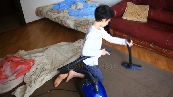 Le garçon nettoie le tapis dans la chambre avec un aspirateur — Video