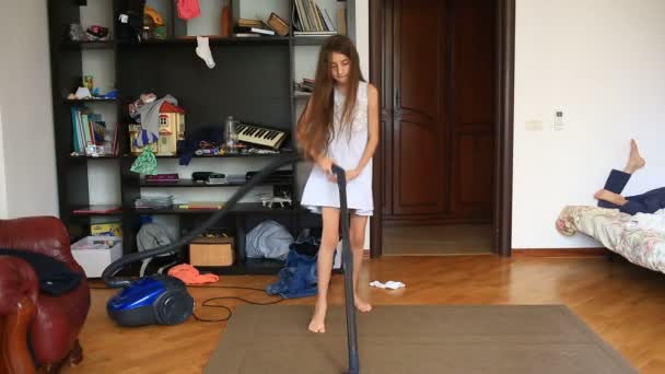 Gadis itu membersihkan karpet di ruangan dengan vacuum cleaner — Stok Video