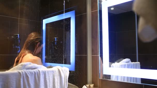 Eine Frau wäscht ihren Kopf und Körper in der Dusche. — Stockvideo