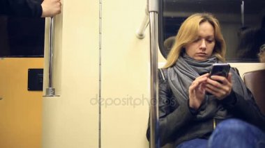 Metro treninin smartphone kullanarak çekici kız. Genç kadın Gözat dokunmatik ekran teknolojisi ile Internet.