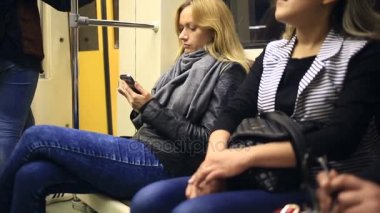 Metro treninin smartphone kullanarak çekici kız. Genç kadın Gözat dokunmatik ekran teknolojisi ile Internet.