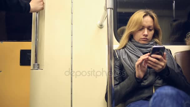 スマート フォンを使用して地下鉄で魅力的な女の子。若い女性は、タッチ スクリーン技術を使用してインターネットを参照します。. — ストック動画