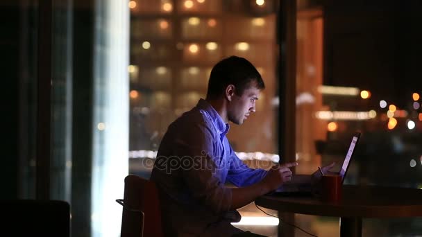 Vackra affärsman arbetar övertid på natten i Stadsledningskontoret. Stadens ljus är synliga i bakgrunden från ett stort fönster — Stockvideo