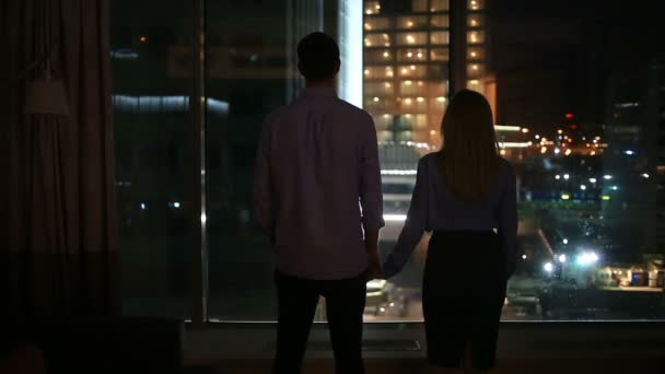 Egy pár, a férfiak és nők, látszó-ban egy nagy ablak, egy éjszaka a városban. ölelés — Stock videók
