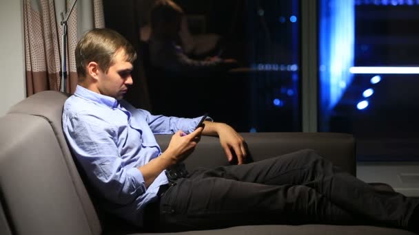 Vista lateral do empresário navegando na internet usando telefone. Em tempo real. janela panorâmica e cidade noturna no fundo . — Vídeo de Stock