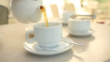 Biri beyaz bir kupa beyaz porselen demlik çay dökülen