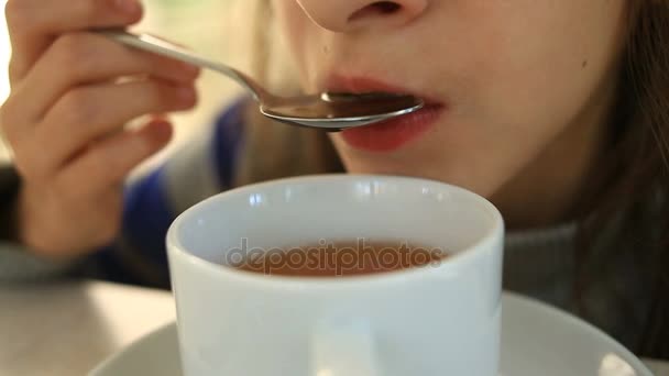 Un bambino beve tè caldo con un cucchiaio in un caffè — Video Stock