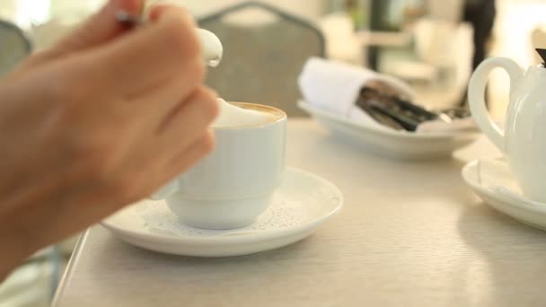 Uma criança bebe chá quente com uma colher em um café — Vídeo de Stock