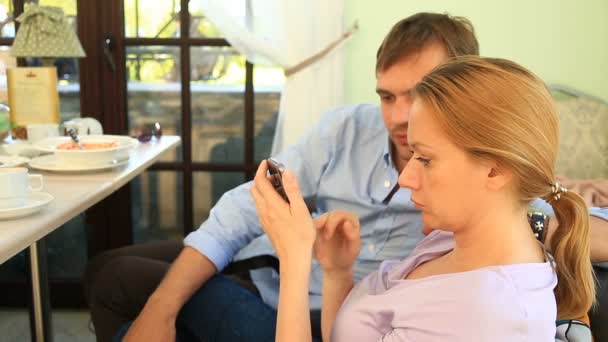 Les gens mangent dans un café, un homme mange un mécontent, une femme regarde son téléphone. Conflits de relations — Video