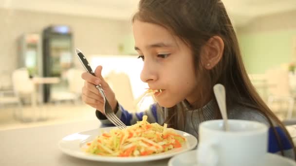 El niño come una ensalada de col vegetariana en un restaurante — Vídeos de Stock