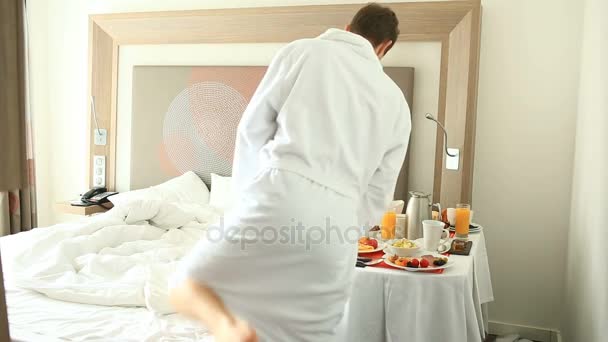 Pareja joven hombre y mujer desayunando en la cama en el apartamento — Vídeos de Stock