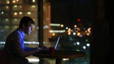 Fazla mesai çalışma gece ofisler içinde güzel iş adamı. Şehir ışıkları arka plan büyük bir pencere görünür