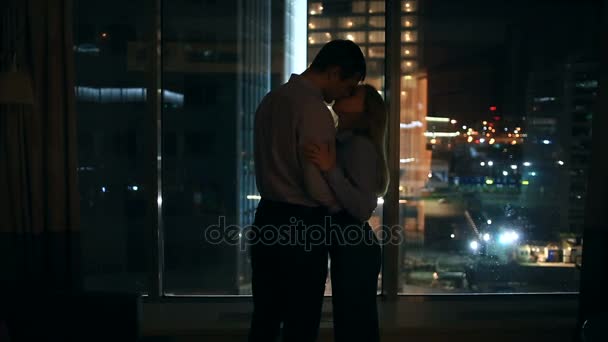Ένα ζευγάρι των ανδρών και των γυναικών που αναζητούν σε ένα μεγάλο παράθυρο σε μια πόλη το βράδυ. αγκαλιά — Αρχείο Βίντεο