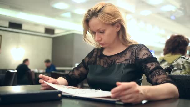 Vrouw in een café. Vrouw kijkt naar het menu in een café — Stockvideo