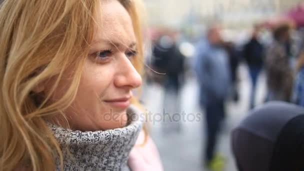 Eine müde Frau in rosa Mantel und Pullover steht mitten auf einer belebten Straße und schreckt vor der Kälte zurück — Stockvideo