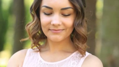 Kahverengi gözleri gülümseyerek ve kameraya bakarak şirin güzel genç esmer kızla