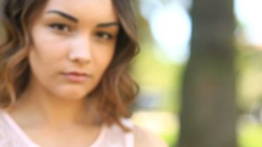 Kahverengi gözleri gülümseyerek ve kameraya bakarak şirin güzel genç esmer kızla