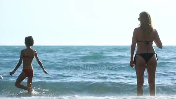 Мама и дочь с длинными волосами в купальниках, купаются в море — стоковое видео