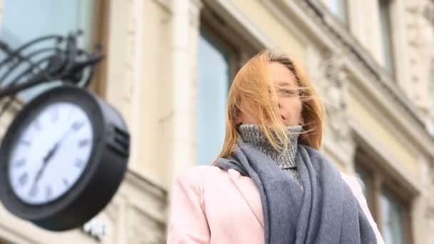 一个女人在一件粉红色的外套和毛衣是站在拥挤的街道，时钟附近，等待会议 — 图库视频影像