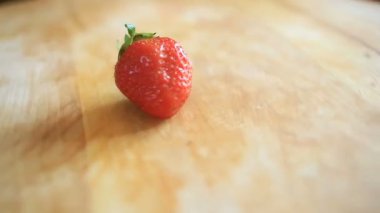 Kendi ekseni etrafında döner bir ahşap tahta üzerinde bir çilek berry yatıyor