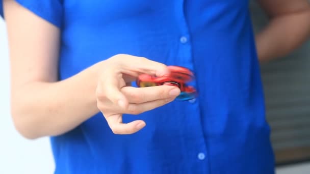 Fileur à main multicolore, rouge-jaune-bleu, ou fileur agitant, tournant sur la main des hommes. Femme filant un Fidget Spinner dans la rue 