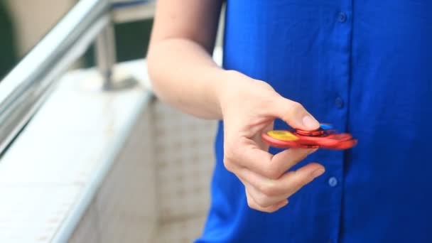 Mångfärgade, röd-gul-blå hand spinner eller fidgeting spinner, roterar på mans hand. Kvinna som snurrar en rastlösa Spinner på gatan — Stockvideo