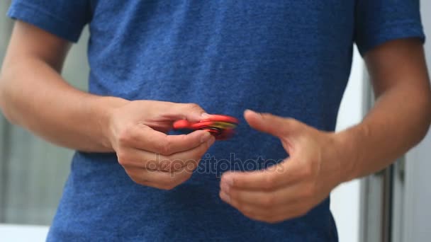 Multicolored, red-yellow-blue hand spinner, or fidgeting spinner, rotating on mans hand. — Stock Video