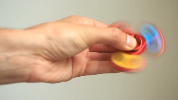 Mångfärgade, röd-gul-blå hand spinner eller fidgeting spinner, roterar på mans hand. — Stockvideo