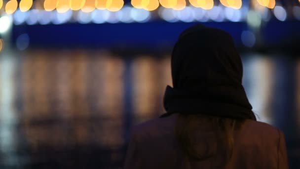 Een paar van man en vrouw die kijken naar de stad van de nacht. 'S nachts flikkeren de lichtjes van de stad op het water. Tuibrug over de rivier — Stockvideo