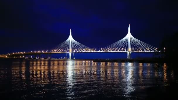 At night, the lights of the city flicker on the water. Cable-stayed bridge across the river — Stock Video