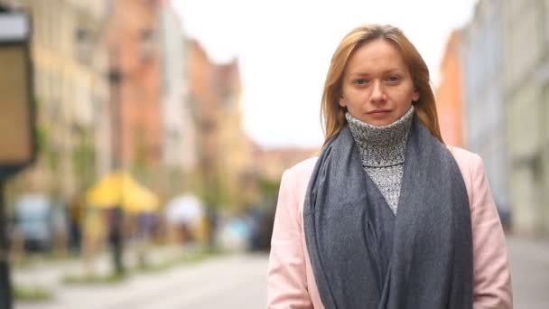 Eine müde Frau in rosa Mantel und Pullover steht mitten auf einer belebten Straße und schreckt vor der Kälte zurück — Stockvideo