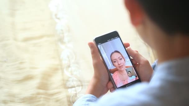 Niño adolescente sostiene un video chat con una mujer en un teléfono inteligente — Vídeo de stock