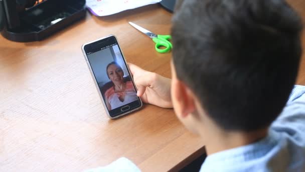 Boy teenager holds a video chat with a woman on a smartphone — Stock Video