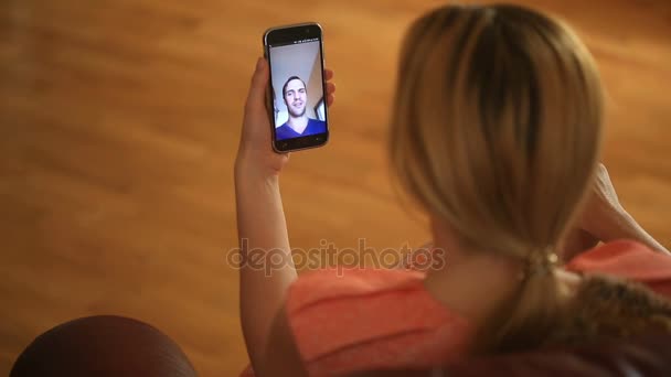 Una mujer está sosteniendo un video chat con un hombre en un teléfono inteligente. Hablan divertido y ríen — Vídeos de Stock