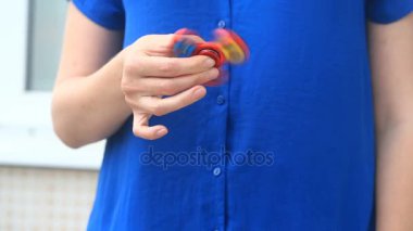 Çok renkli, Kırmızı-Sarı-Mavi el spinner veya üzerinde dönen fidgeting spinner el mans. Kadın sokakta kıpır Spinner iplik