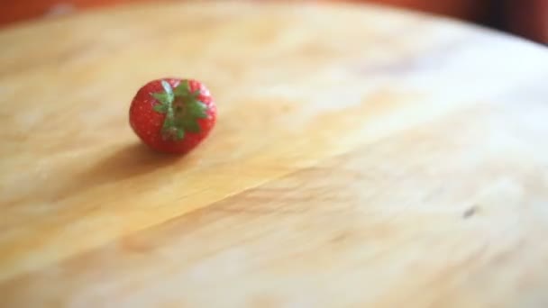 Uma baga de morango encontra-se em uma tábua de madeira que gira em torno de seu eixo — Vídeo de Stock