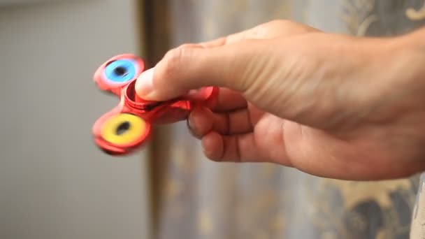 Mångfärgade, röd-gul-blå hand spinner eller fidgeting spinner, roterar på mans hand. — Stockvideo