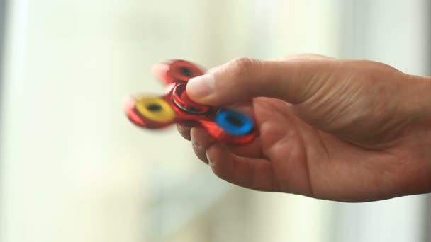Multicolored, red-yellow-blue hand spinner, or fidgeting spinner, rotating on mans hand. — Stock Video