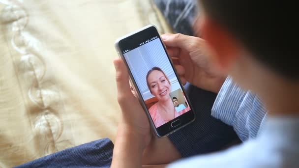 Niño adolescente sostiene un video chat con una mujer en un teléfono inteligente — Vídeo de stock