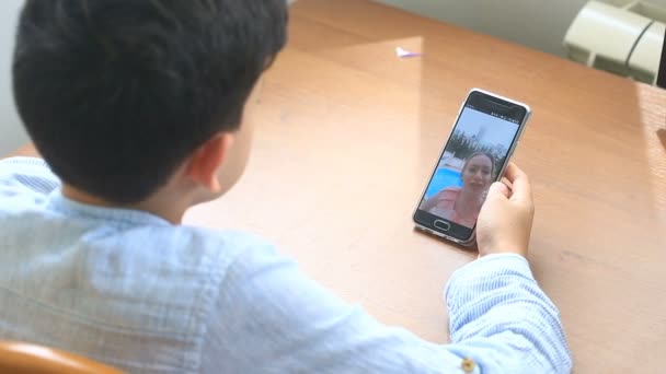 Niño adolescente sostiene un video chat con una mujer en un teléfono inteligente — Vídeo de stock