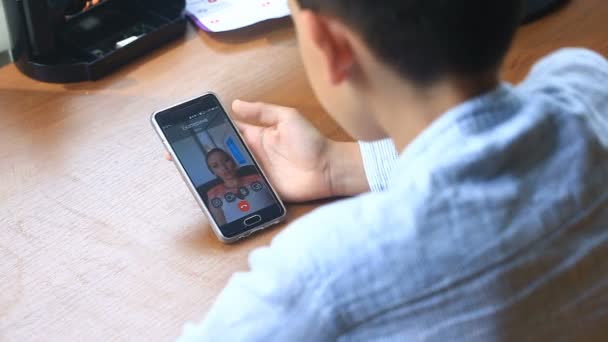 Niño adolescente sostiene un video chat con una mujer en un teléfono inteligente — Vídeo de stock