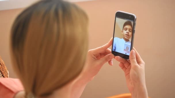 En kvinna bedriver videochat på en smartphone med ett barn — Stockvideo