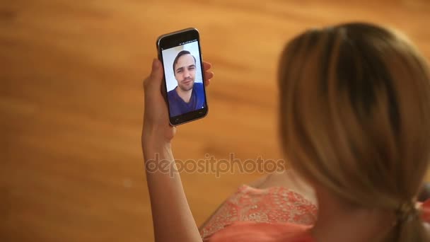 Жінка тримає відеочат з чоловіком на смартфоні. Вони розмовляють весело і смішно — стокове відео