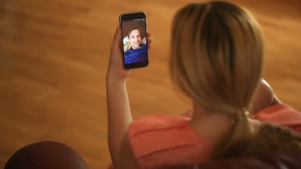 Una donna sta tenendo una video chat con un uomo su uno smartphone. Parlano di divertimento e ridono — Video Stock