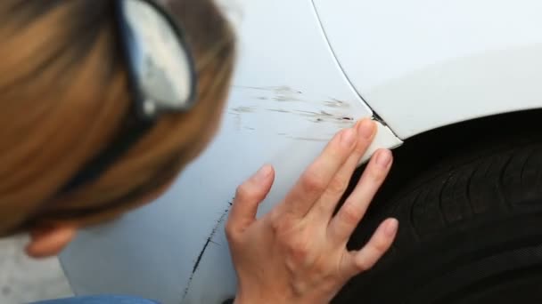 Een beschadigd voertuig te kijken. Vrouw blond inspecteert auto schade na een ongeval — Stockvideo