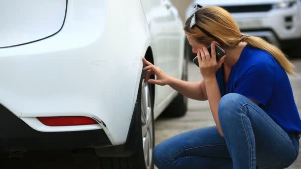 Глядя на поврежденный автомобиль. Блондинка осматривает повреждения автомобиля после аварии — стоковое видео
