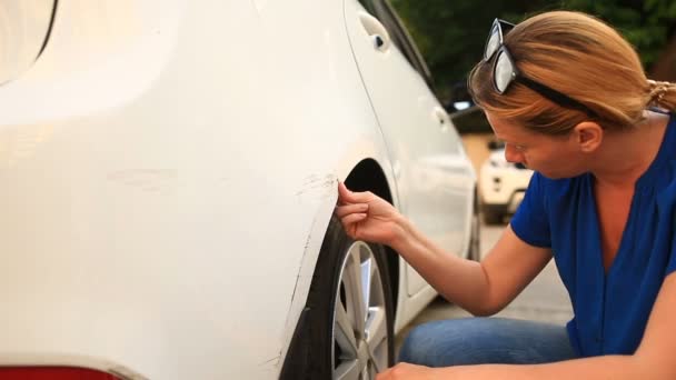 Дивлячись на пошкоджений автомобіль. Жінка блондинка оглядає пошкодження автомобіля після аварії — стокове відео