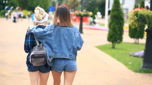 Två flickvänner promenera ner staden gatan och dricka en milkshake från en disponibel cup — Stockvideo