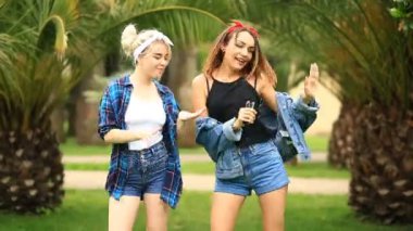 İki arkadaş şehir parkta bir bankta oturmak ve bir milkshake tek kullanımlık bir bardak içki