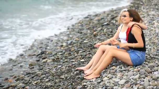 Duas namoradas bonitas estão sentadas na praia e conversando — Vídeo de Stock